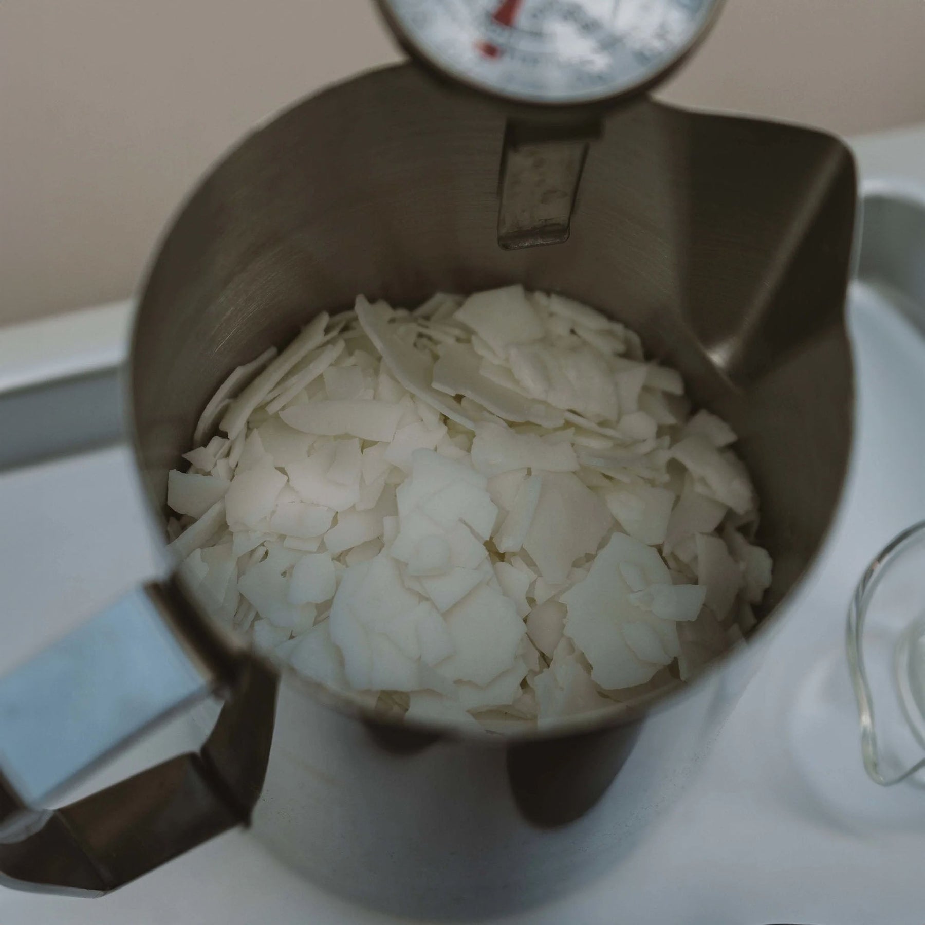 Soy wax flakes melting in a candle wax pouring jug